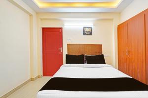 a bedroom with a large bed with a red door at Hotel O Purasaiwalkam in Chennai