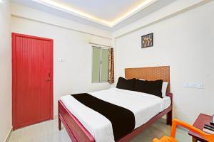 a bedroom with a large bed with a red door at Hotel O Purasaiwalkam in Chennai