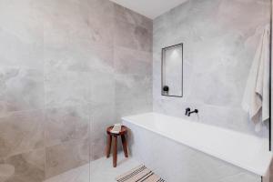 une salle de bain blanche avec une baignoire et un miroir dans l'établissement HOBART 3 Bedroom, à West Hobart 47 autres photos