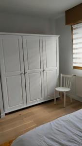 a bedroom with white cabinets and a white chair at Chez YEP in Anzin-Saint-Aubin +2 photos