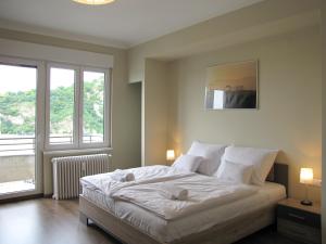 una camera da letto con un grande letto bianco con due finestre di Empire of Liberty a Budapest