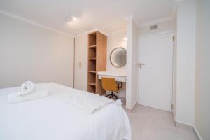 Un dormitorio blanco con una cama blanca y un escritorio. en Seaside Serenity, en Ballito 18 fotos más