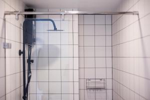 a shower in a bathroom with white tiled walls at FantaSea condo Kamala 204 in Kamala Beach +10 photos