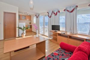 a living room with a red couch and a desk at Семеен хотел Бриз in Sozopol