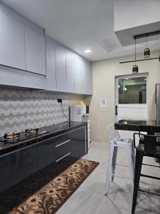 a kitchen with white cabinets and a black counter top at Macchiato Homestay in Klang