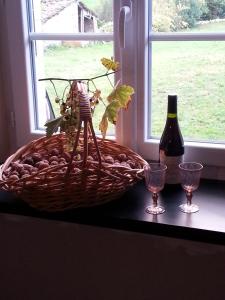 a basket of grapes and a bottle of wine and glasses at La Maison Des Badons in Saint-Basile