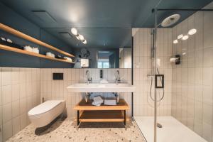 Un baño con lavabo, inodoro y ducha. en HOP Apartments & Suites, en Interlaken 190 fotos más
