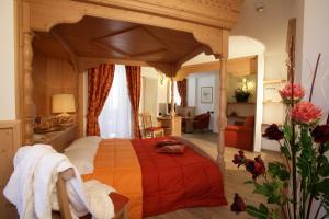 a bedroom with a canopy bed with a red blanket at Hotel Garni La Roccia in Andalo