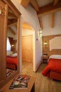 1 dormitorio con 2 camas y espejo en Hotel Garni La Roccia, en Andalo