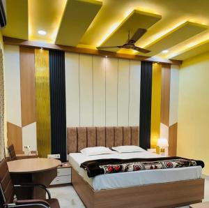 a bedroom with a bed and a table and a ceiling at PLAY RAJKUMAR GARDEN & ROOMs in Chhatikara