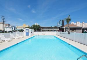 une grande piscine avec des chaises et un bâtiment dans l'établissement Seashire Inn & Suites, à Virginia Beach