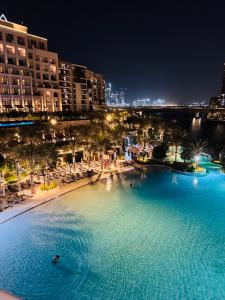a large pool of water next to a beach at night at Apartment In Creek Beach in Dubai