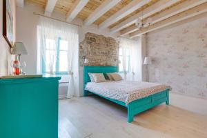 a bedroom with a blue bed and a brick wall at Heritage Hotel Chersin in Fažana