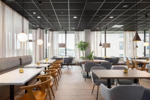 a restaurant with tables and chairs and windows at Radisson Hotel Haugesund in Haugesund