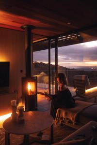 a woman sitting in a living room with a fireplace at Willunga Ridge in Willunga