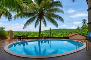 a pool with a table and a palm tree at Quadruple Comfort Calangute Goa in Calangute