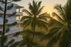 a building with palm trees in front of it at Quadruple Comfort Calangute Goa in Calangute