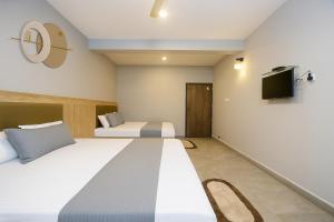 a hotel room with two beds and a flat screen tv at Quadruple Comfort Calangute Goa in Calangute