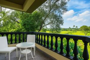 a balcony with chairs and a table and a view at Quadruple Comfort Calangute Goa in Calangute +4 photos