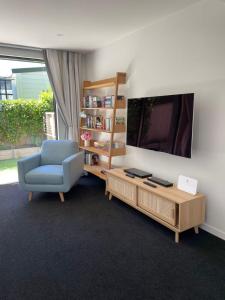ウェリントンにあるExecutive Townhouse in Island Bay with Free Parkingのリビングルーム(青い椅子、テレビ付)