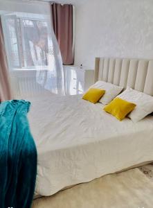 a white bed with two yellow pillows on it at Биржан Сал центр 2 к in Taldykorgan