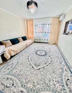 a living room with a couch and a rug at Биржан Сал центр 2 к in Taldykorgan