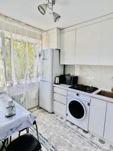 a white kitchen with a stove and a refrigerator at Биржан Сал центр 2 к in Taldykorgan