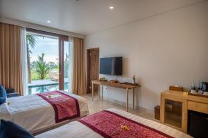 a hotel room with two beds and a television at Kayun Retreat Mas Suite in Ubud