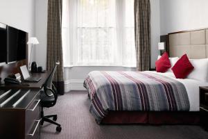 a hotel room with a bed with red pillows at The Grand at Trafalgar Square in London