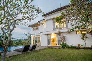 a white house with a pool and a yard at Kayun Retreat Mas Suite in Ubud