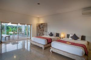 a bedroom with two beds and a patio with a table at Kayun Retreat Mas Suite in Ubud +91 photos