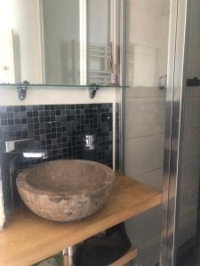 baño con lavabo de piedra en una encimera de madera en One Bedroom Flat with Large Balcony overlooking the sea in an Art Deco building, en Saint-Lunaire