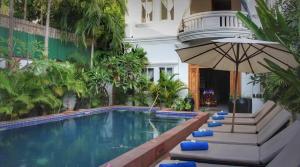 a swimming pool with an umbrella next to a building at Villa Wat Bo in Siem Reap