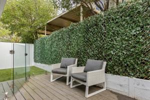 two chairs sitting on a deck in front of a hedge at Spa Haus Belmont- 2 King beds, Spa, Pets Welcome, Beaches, Golf, Shopping, Geelong in Belmont