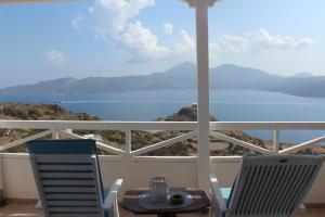 a table and chairs on a balcony with a view of the water at Studios Betty in Plaka Milou