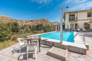 a pool with a table and chairs next to a house at Casa Hitos in Monachil