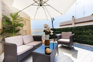 eine Terrasse mit einem Sofa, Stühlen und einem Sonnenschirm in der Unterkunft Villa Amateia in Syrakus