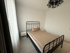 a bed in a white room with a chandelier at REVO LUX Apartament in Baia Mare