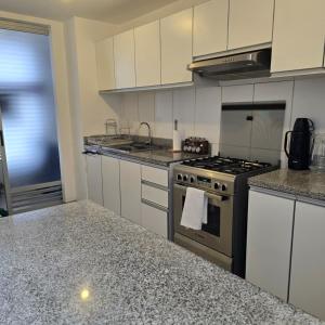 a kitchen with white cabinets and a stove top oven at Departamento Arequipa- PERUMIN 2025 in Paucarpata