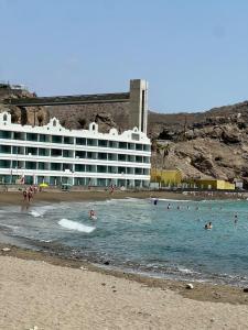 ein Hotel am Strand mit Leuten im Wasser in der Unterkunft Quiet Corner by the Beach in Mogán
