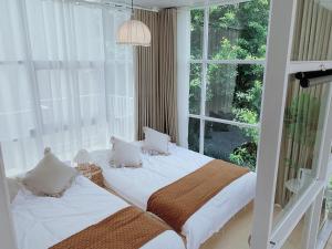 Dos camas en una habitación con una gran ventana. en Sinanli Flower House Courtyard, en Jiazaiwei