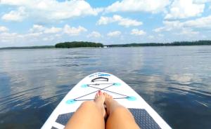 a woman laying on a paddle board on a lake at Klimatyzowany Domek z Sauną w lesie z posesją na wyłączność Mazury Prażmowo in Prażmowo
