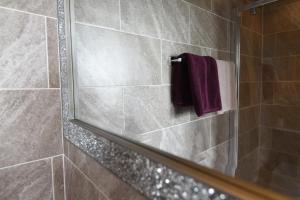 um chuveiro com um espelho e uma toalha roxa em No.18 em Lowestoft