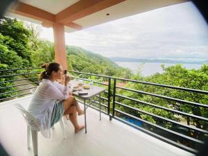 a woman sitting at a table on a balcony at CJ's Place Mabini in Mabini