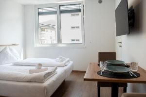 a bedroom with a bed and a table and a window at myQuartier Urban Residences digital self check in in Innsbruck