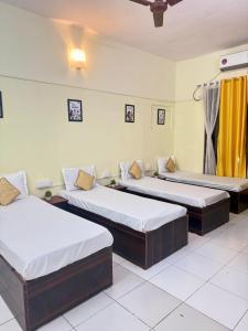 drie bedden in een kamer met gele gordijnen bij Elite Hostel- A Perfect Stay for Working Professional,Travellers in Pune