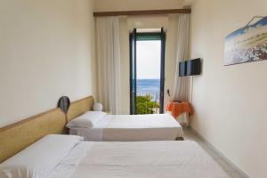 a hotel room with two beds and a window at Albergo Palazzo in Santa Cesarea Terme