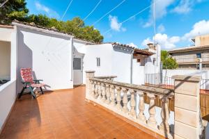 a balcony of a white house with a chair at La Casa Di Ines in Porto Cristo