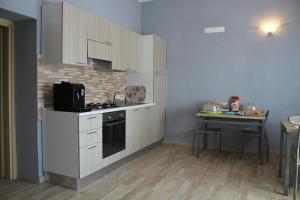 una cucina con armadi bianchi e un tavolo di B&B La Cantoniera a San Teodoro