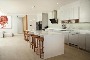 une cuisine avec des placards blancs et un grand îlot avec des tabourets de bar dans l'établissement Bangtao Luxury 4 bedroom villa Lux Pride, à Ban Pak Lak